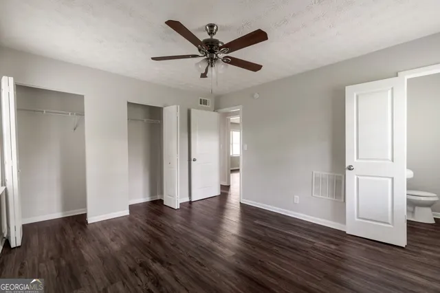 a view of an empty room with wooden floor and a ceiling fan