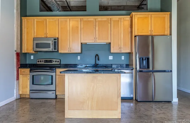 a kitchen with stainless steel appliances granite countertop a refrigerator and a stove top oven