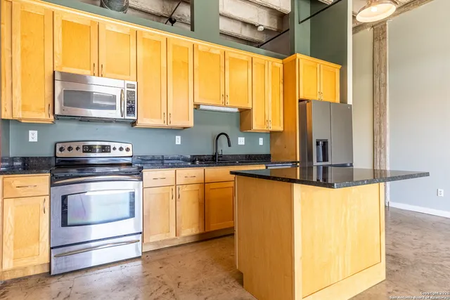 a kitchen with stainless steel appliances granite countertop a sink and a refrigerator