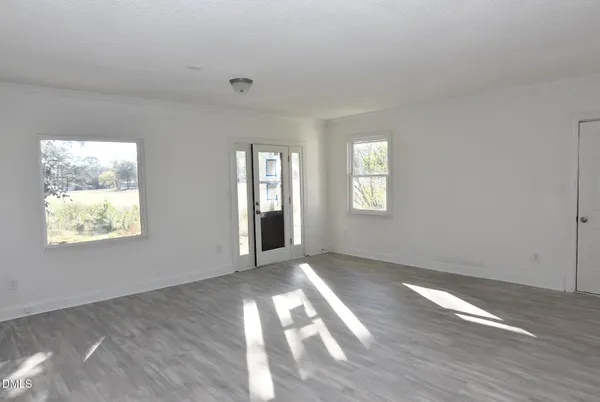 a view of an empty room with wooden floor and a window