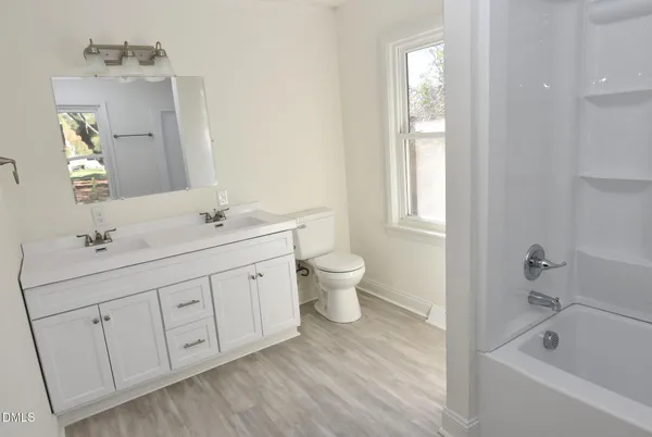 a bathroom with a double vanity sink a toilet and a bathtub