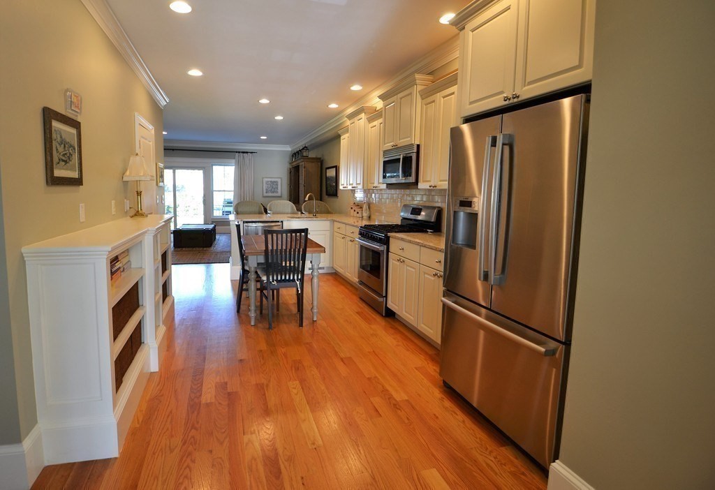 11 Tufts Road, Unit 11 Winchester, MA 01890 - Photo 3 of 18 a kitchen with stainless steel appliances a refrigerator a stove top oven a sink dishwasher and a dining table with wooden floor