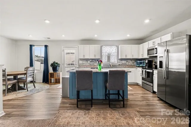 a kitchen with kitchen island a dining table chairs refrigerator and cabinets