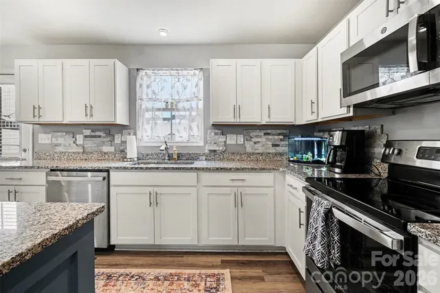 a kitchen with stainless steel appliances granite countertop a stove a sink and a microwave
