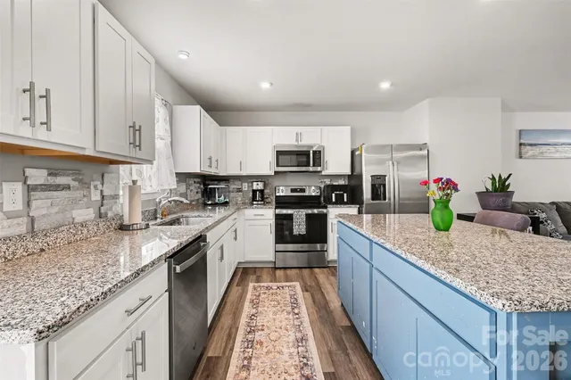 a kitchen with kitchen island granite countertop a sink counter top space appliances and cabinets