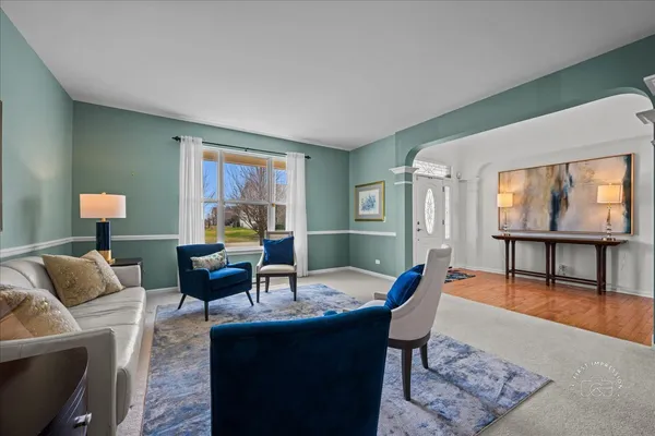 a living room with furniture a rug a lamp and a large window