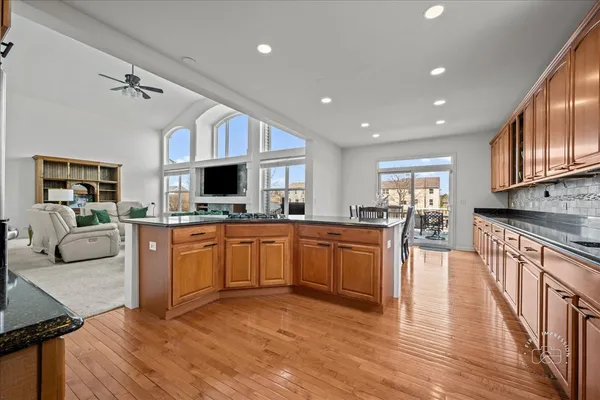 a large kitchen with stainless steel appliances granite countertop a stove top oven a sink dishwasher a dining table and chairs with wooden floor