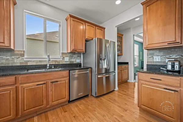 a kitchen with granite countertop stainless steel appliances a refrigerator cabinets and wooden floor