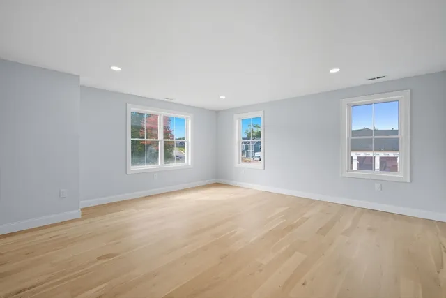 a view of an empty room with a window and wooden floor
