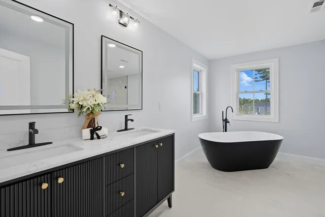 a spacious bathroom with a double vanity sink a mirror and a bathtub