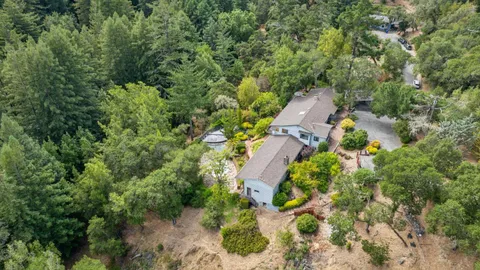 an aerial view of residential house with outdoor space and trees all around