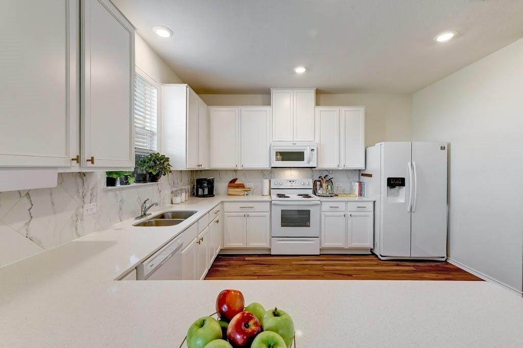 13916 Inaugural Street Manor, TX 78653 - Photo 14 of 28 A well-appointed kitchen showcasing elegant marble backsplash and gleaming countertops.