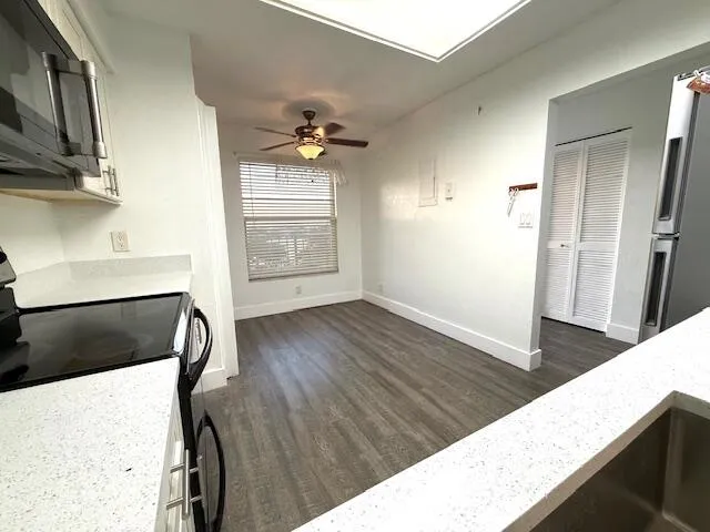 an empty room with wooden floor a ceiling fan and windows