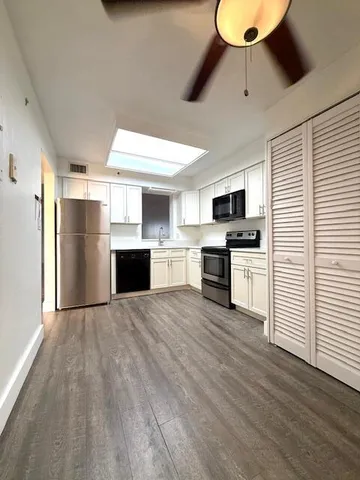 an empty room with wooden floor a ceiling fan and windows