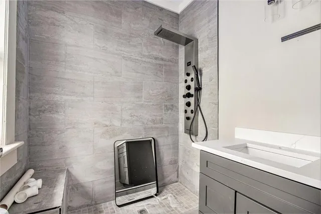 a bathroom with a granite countertop sink a mirror and shower