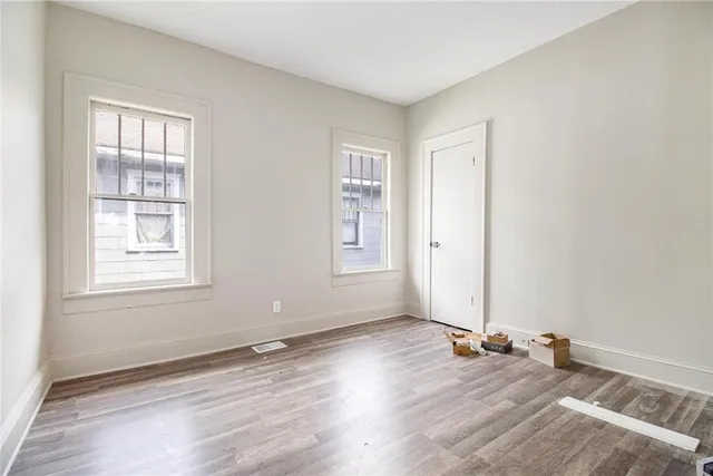 an empty room with wooden floor and windows