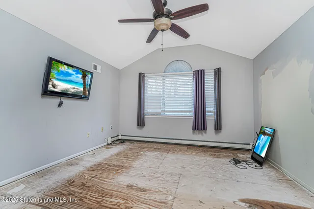 an empty room with wooden floor fan and windows