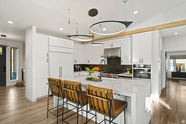 4499 North Seven Bridges Road, Unit 9 Eden, UT 84310 - Photo 7 of 65 Modern kitchen featuring white shaker cabinetry, an expansive waterfall island, integrated stainless steel appliances, and wood-finish flooring