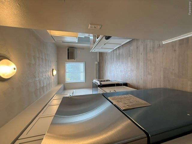 Kitchen featuring stainless steel appliances, white cabinetry, wood-finish flooring, and a window