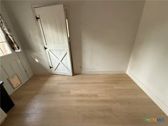 an empty room with wooden floor and door