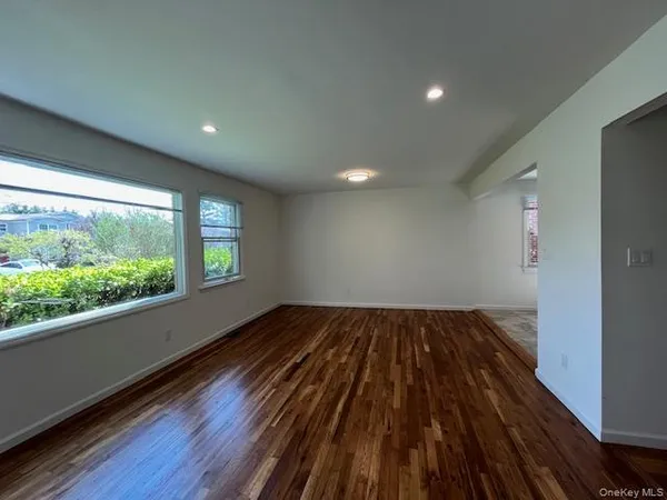 a view of wooden floor in an empty room with a window
