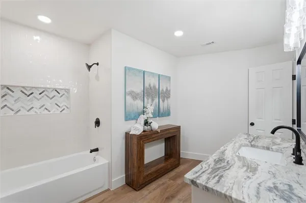 a bathroom with a tub sink and mirror