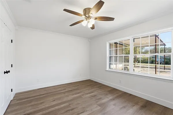 an empty room with wooden floor and windows