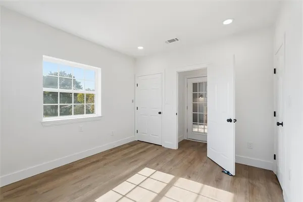 an empty room with wooden floor and windows