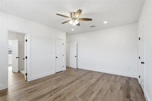 an empty room with wooden floor and a ceiling fan
