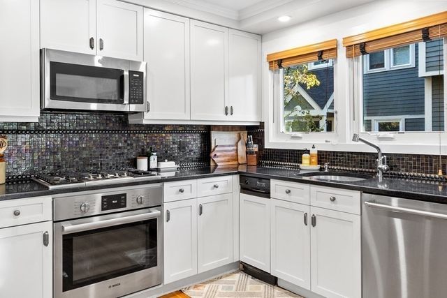 a kitchen with stainless steel appliances granite countertop a stove a sink and a microwave