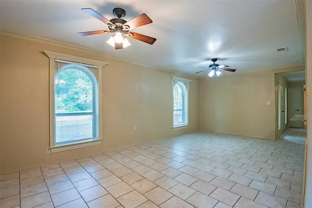 a view of an empty room with window chandelier fan