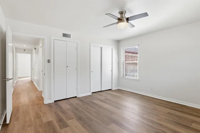 an empty room with wooden floor and ceiling fan