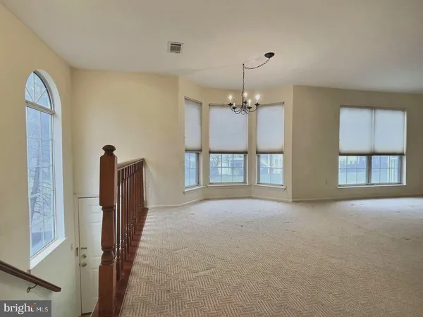 a view of an empty room with chandelier and a window