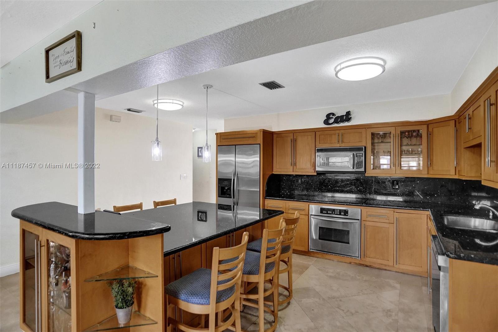 10401 Southwest 53rd Street Miami, FL 33165 - Photo 40 of 53 a kitchen with stainless steel appliances kitchen island granite countertop a stove a sink and a microwave