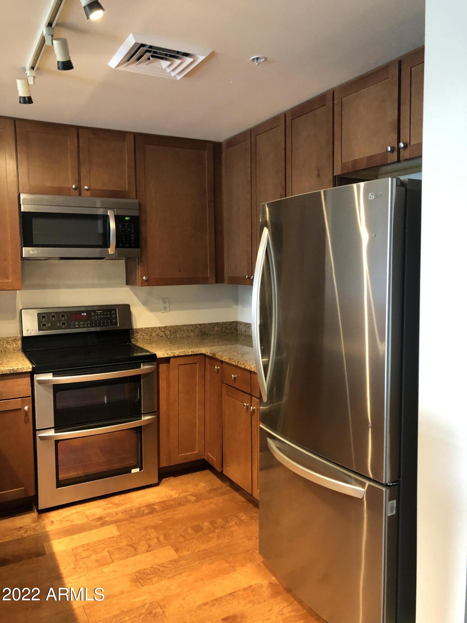 310 South 4th Street, Unit 1507 Phoenix, AZ 85004 - Photo 15 of 24 a kitchen with granite countertop a refrigerator and a sink