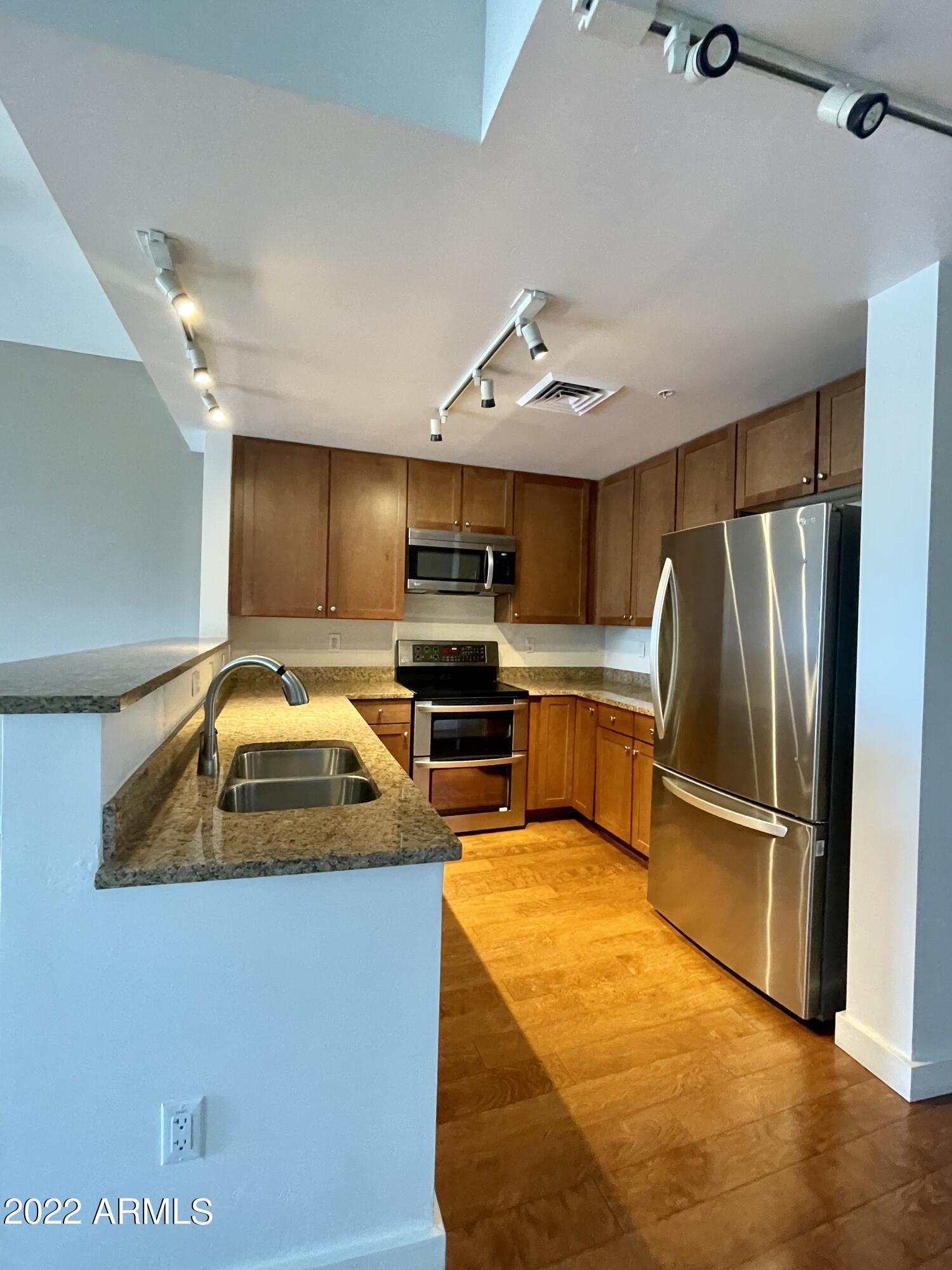 310 South 4th Street, Unit 1507 Phoenix, AZ 85004 - Photo 16 of 24 a kitchen with stainless steel appliances granite countertop a sink a stove and refrigerator