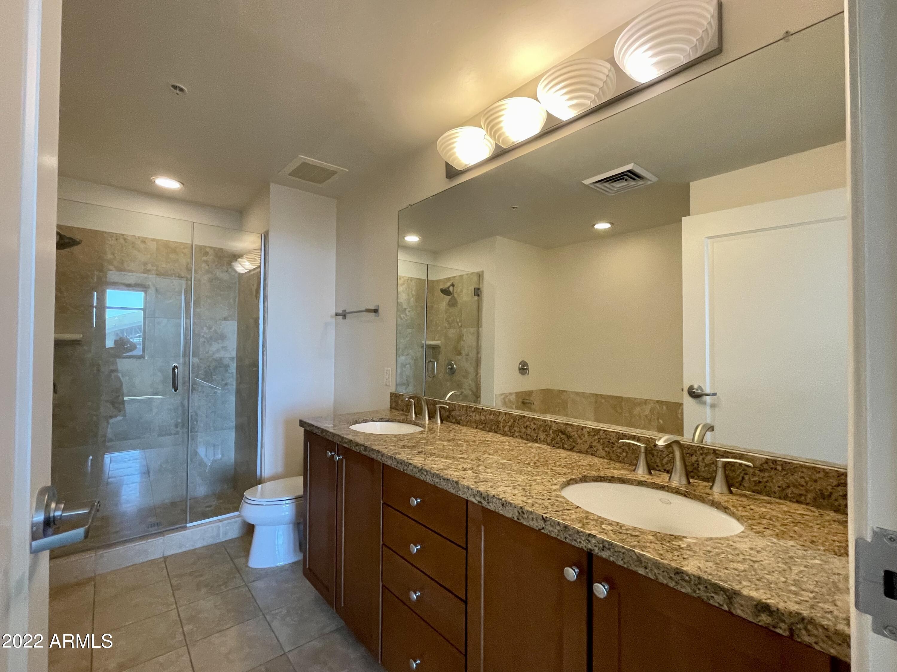 310 South 4th Street, Unit 1507 Phoenix, AZ 85004 - Photo 17 of 24 a bathroom with a granite countertop sink mirror and shower