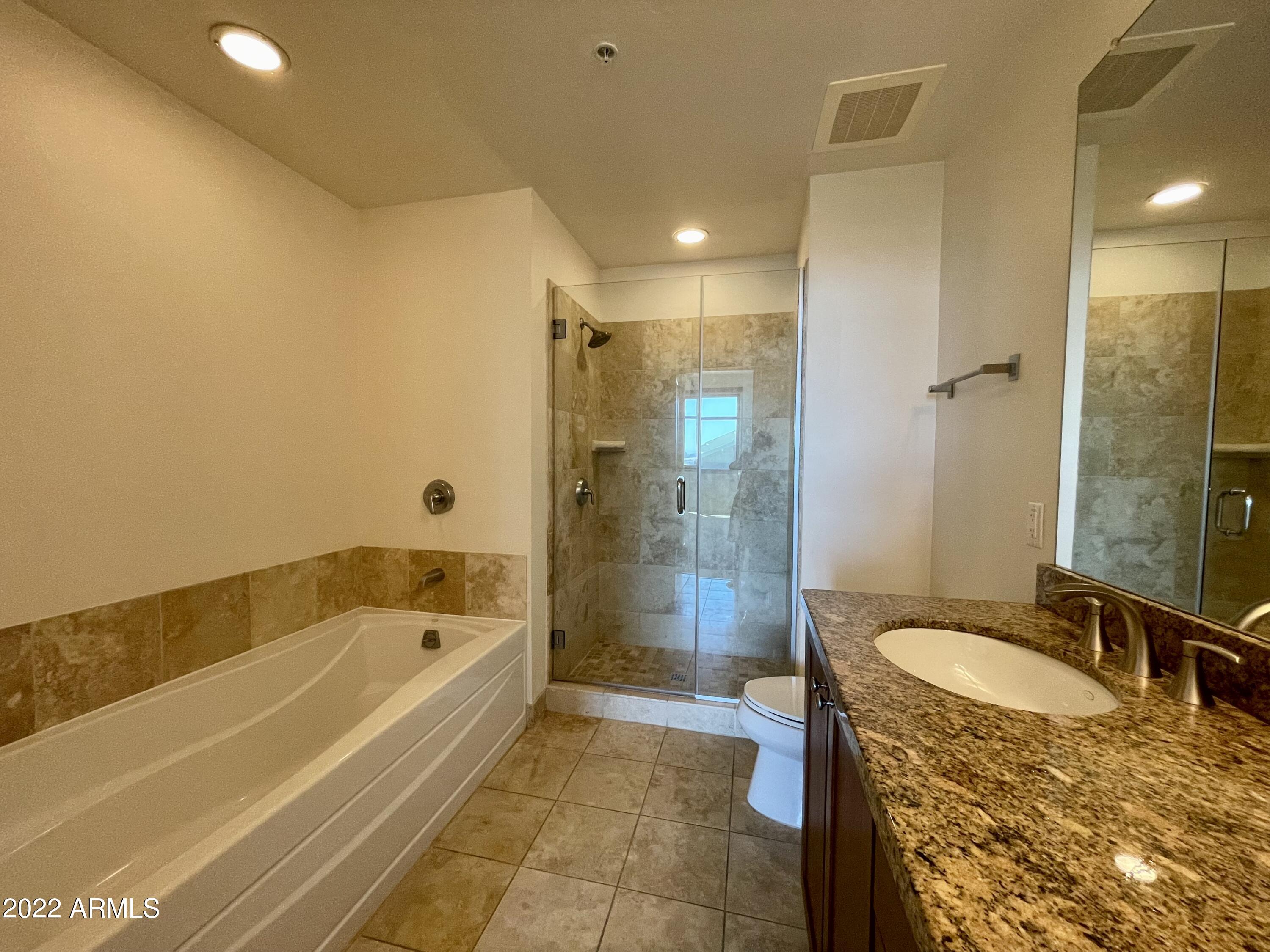 310 South 4th Street, Unit 1507 Phoenix, AZ 85004 - Photo 18 of 24 a spacious bathroom with a granite countertop tub sink a shower and a mirror