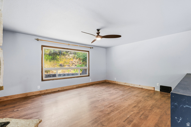 1410 Sumac Drive Logan, UT 84321 - Photo 7 of 28 Bright room featuring wood-finish flooring, a large picture window with wooden trim, and a ceiling fan with integrated lighting