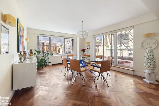 a dining room with wooden floor a chandelier a glass table and chairs