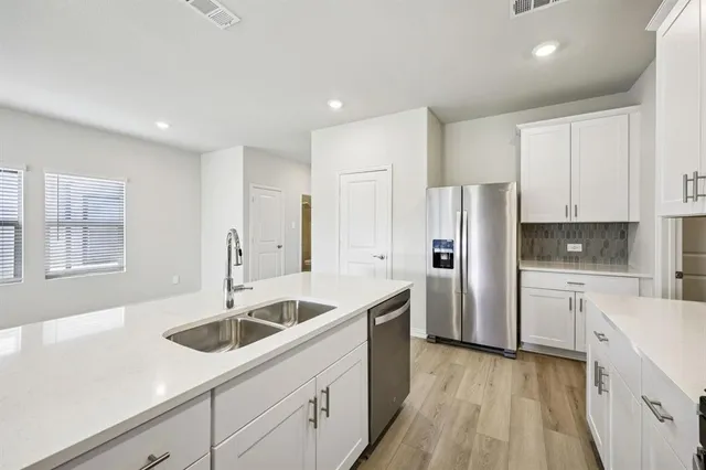 a kitchen that has a sink a refrigerator and cabinets