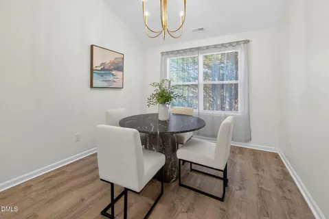 a view of a dining room with furniture a potted plant and wooden floor