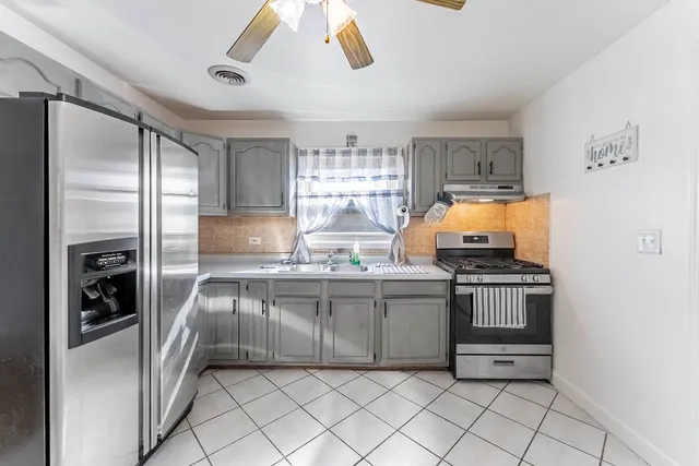 a kitchen with stainless steel appliances granite countertop a refrigerator a stove and a sink