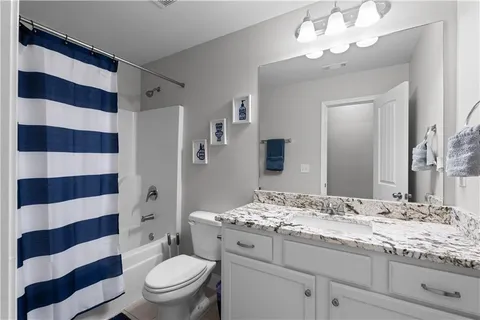 a bathroom with a granite countertop sink a toilet a mirror a shower and vanity