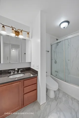 a bathroom with a granite countertop sink a toilet a mirror and shower
