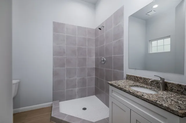 a bathroom with a granite countertop sink a toilet and shower