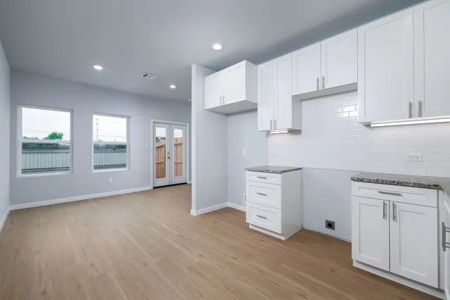 a kitchen with white cabinets and wooden floor