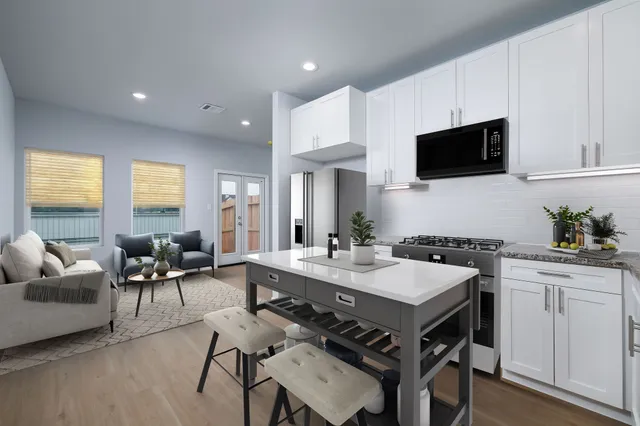 a living room with stainless steel appliances granite countertop furniture a fireplace a flat screen tv and a window