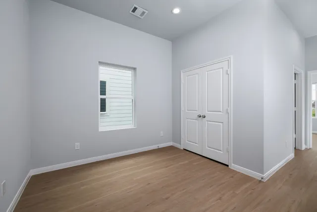 an empty room with wooden floor and window