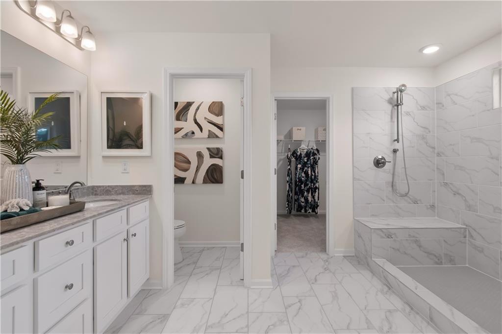 295 Abbotts Xing Circle Covington, GA 30016 - Photo 29 of 34 a spacious bathroom with a granite countertop sink a mirror a shower and a bathtub